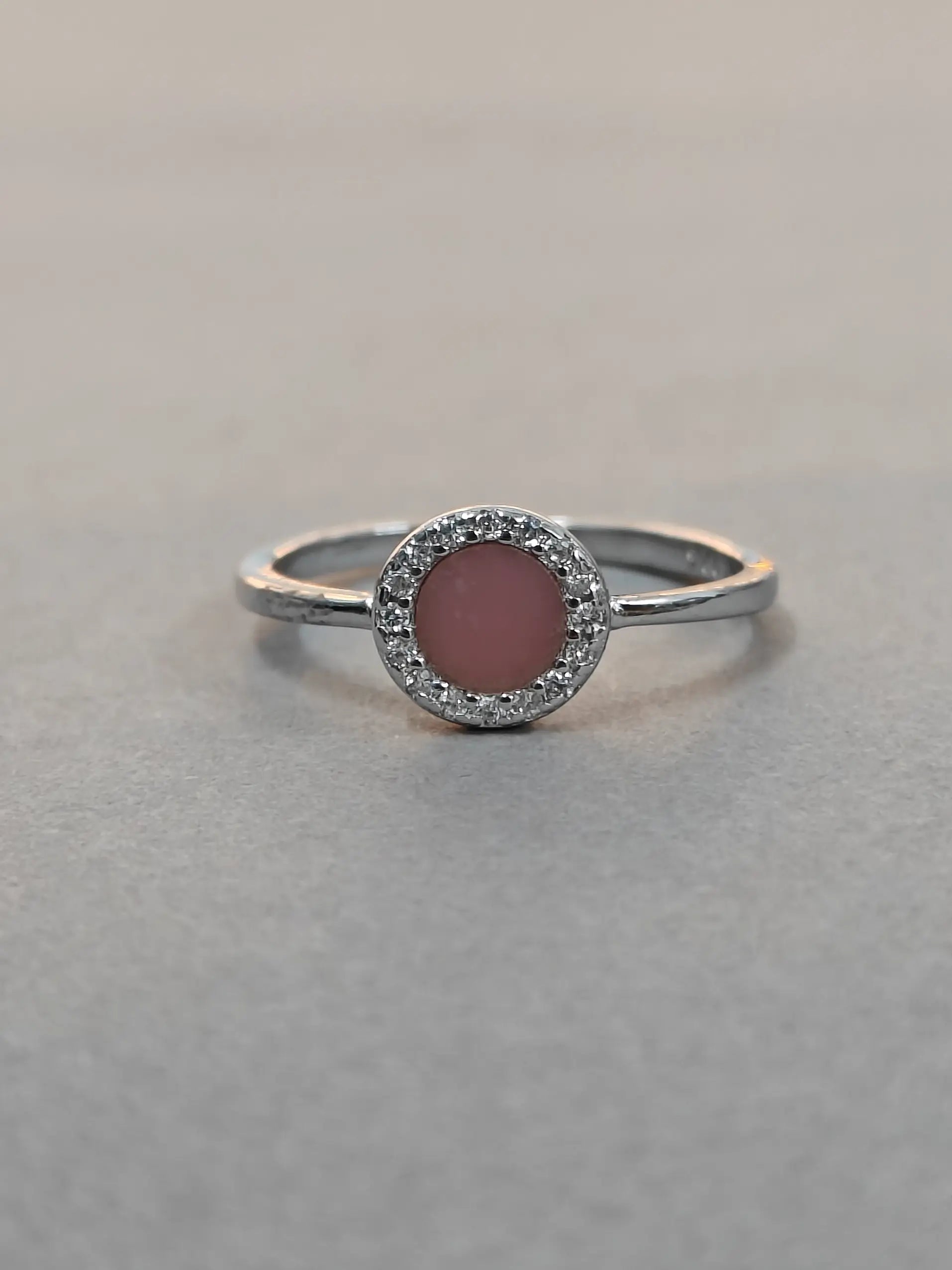 Silver ring with a pink gemstone on a gray background